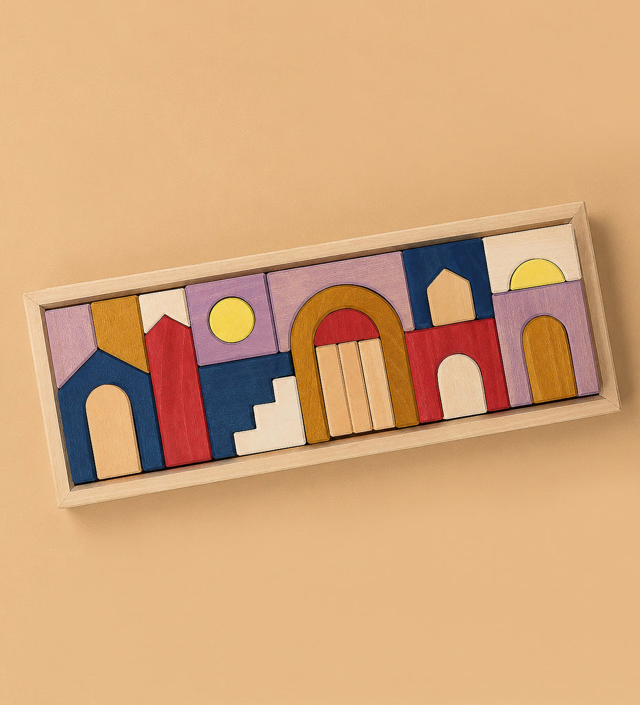 Grimm's Panorama Building Set features colorful wooden blocks in red, blue, yellow, white, and natural wood tones with arches, steps, and circles arranged on a rectangular tray as abstract architectural shapes.