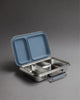 A Haps Nordic stainless steel lunch box with two compartments and an ocean blue lid is open on a gray background.