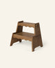 The Häti at Home - Margot Step Stool, a small wooden kids’ stool with two steps and scalloped edges crafted from medium brown wood, is shown against a plain light background.