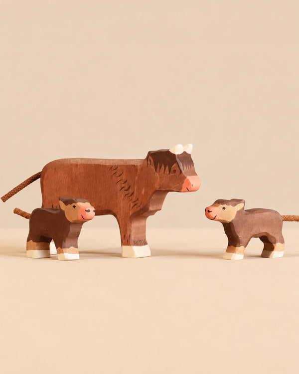 Holztiger Handmade Wooden Highland Cow Family Set featuring a handcrafted wooden Highland cow figure standing with two smaller calves, perfect for open-ended play.