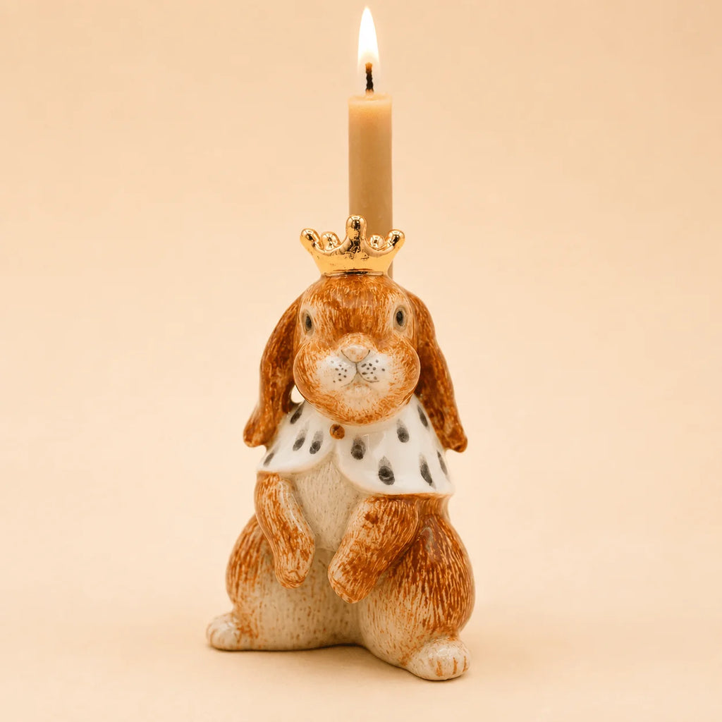 The Highness Hare Cake Topper - Final Sale (ships in one week) features a ceramic bunny with a gold crown, royal cape, and a lit beige candle atop its head—perfect as a collectible keepsake.