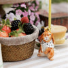 The Highness Hare Cake Topper - Final Sale (ships in one week) features a crowned rabbit holding a yellow candle beside berries and cake—a charming hand-painted birthday decoration for your celebration.