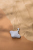 A small, gray ceramic figurine of a Handmade Wooden Stingray partially submerged in fine sand against a light brown backdrop, creating a serene and minimalist aesthetic with child-safe paint.