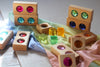 Bauspiel Gem Blocks with Lucent Cubes, 45-Piece Set, featuring wooden blocks with inset colorful translucent gems and loose translucent cubes arranged on a layered silk cloth.
