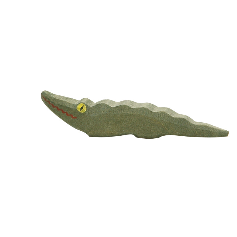 A simple handcrafted Ostheimer Small Crocodile toy with a wavy body painted green, and details such as red mouth and yellow eye, isolated on a white background.