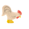 A handcrafted wooden toy figure of an Ostheimer Rooster, painted in natural wood tones with red and yellow accents, standing on a white background.