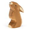 A Ostheimer Rabbit - Ears Low figurine, handcrafted with simplistic details including eyes and ears, stands upright. The background is plain and white, underscoring the natural wood tones and grain.
