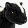 Close-up of a Skunk Stuffed Animal plush toy featuring black fur, a white head stripe, round dark eyes, and a shiny black nose against a plain white background.