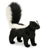 The Skunk Stuffed Animal stands upright with black fur, a bushy tail striped and tipped in white, plus a white stripe from head to back—one of HANSA's realistic plush creations.