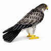 The Falcon Bird Stuffed Animal features lifelike black, gray, and white feathers, yellow feet, and a yellow beak. Hand sewn by HANSA animals, it's perfect for fans of realistic plush toys and stands on a white background.