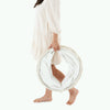 A woman in a flowing white dress holds an open Gathre Vegan Leather Play Tunnel around one leg, standing barefoot on a white background.