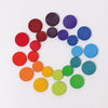 Grimm's Wooden Rainbow Coins (coming soon) feature colorful wooden coins arranged in a spiral on a white background, transitioning from red to purple—ideal tactile pieces for imaginative and creative play.