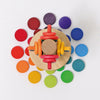 Grimm's Wooden Rainbow Coins (coming soon): Colorful stacking rollers, wooden coins, and rings arranged in a vibrant rainbow pattern, displayed on a white background from an overhead view.