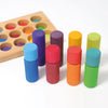 Four wooden Grimm’s Stacking Game Small Rainbow Rollers in blue, red, orange, and green arranged with a wooden color sorting board in the background.