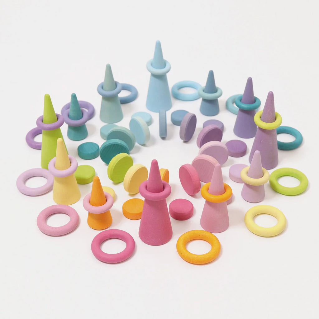 Grimm’s Wooden Pastel Coins are arranged upright and flat on a white background, forming a playful, abstract pattern in soft pastel shades of pink, purple, blue, yellow, and green. Carefully crafted and finished with natural oils to enhance their vibrant hues, these construction pieces add a cheerful touch to any play space.