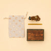 A star-patterned drawstring pouch, the Jaguar Cake Topper - Final Sale (a small handcrafted collectible ceramic jaguar), a yellow stick, and a wooden box with “campholder” on the lid are arranged neatly on a beige background.