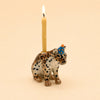A small hand-painted ceramic “Jaguar Cake Topper - Final Sale” figurine, wearing a blue party hat and featuring a lit birthday candle on its back, is displayed against a plain beige background.