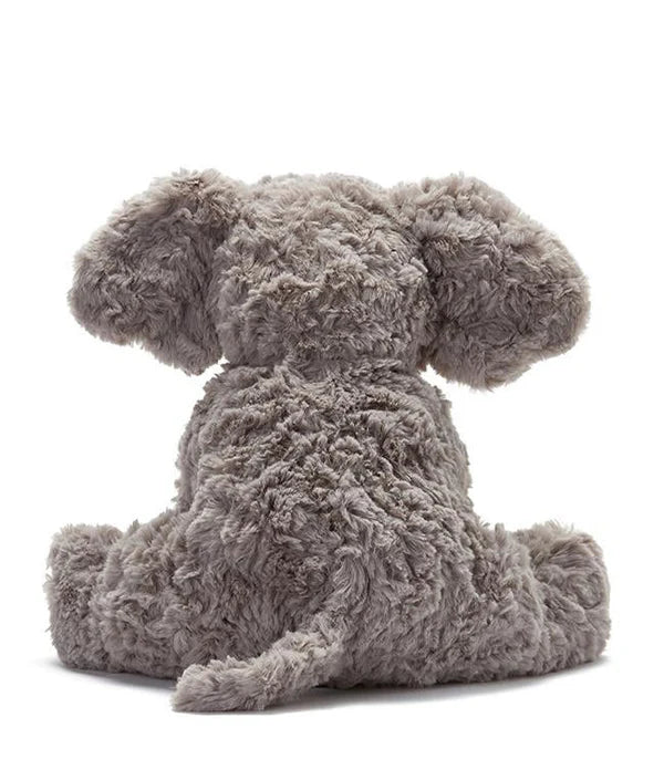 Jimmy the Elephant Stuffed Animal, with its soft grey plush exterior, is captured from behind, highlighting its large ears and short tail as it rests comfortably on a white surface.