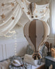 A cozy children's room decorated with the Hot Air Balloon - Gold model, star-shaped wall decor, string lights, draped fabric, and a soft bed with patterned bedding in soothing beige and white tones.