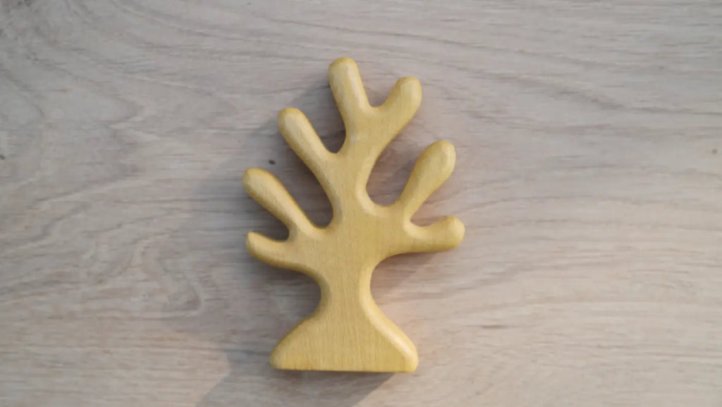 The Handmade Holzwald Yellow Coral is a light wooden toy shaped like a simple tree with five rounded branches, shown on a light wood surface.