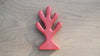 A red, tree-shaped wooden coral with five rounded branches sits on a light wooden surface—perfect for underwater play or as part of your Handmade Holzwald Coral collection.