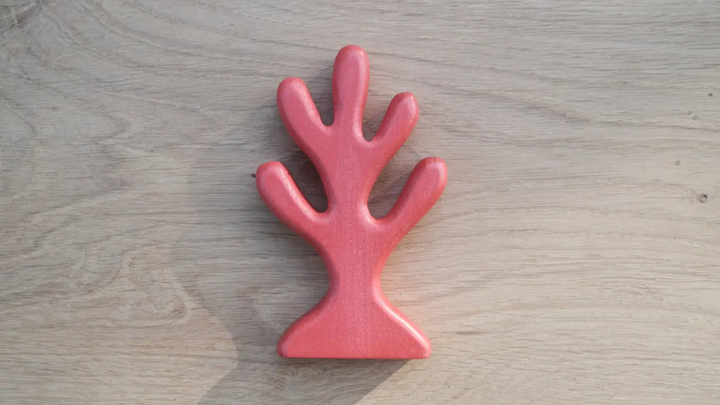 A red, tree-shaped wooden coral with five rounded branches sits on a light wooden surface—perfect for underwater play or as part of your Handmade Holzwald Coral collection.