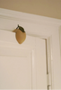 The Konges Sloejd Door Stopper - Lemon, CE-tested and wedge-shaped with a green leaf, props open a white door against its frame.