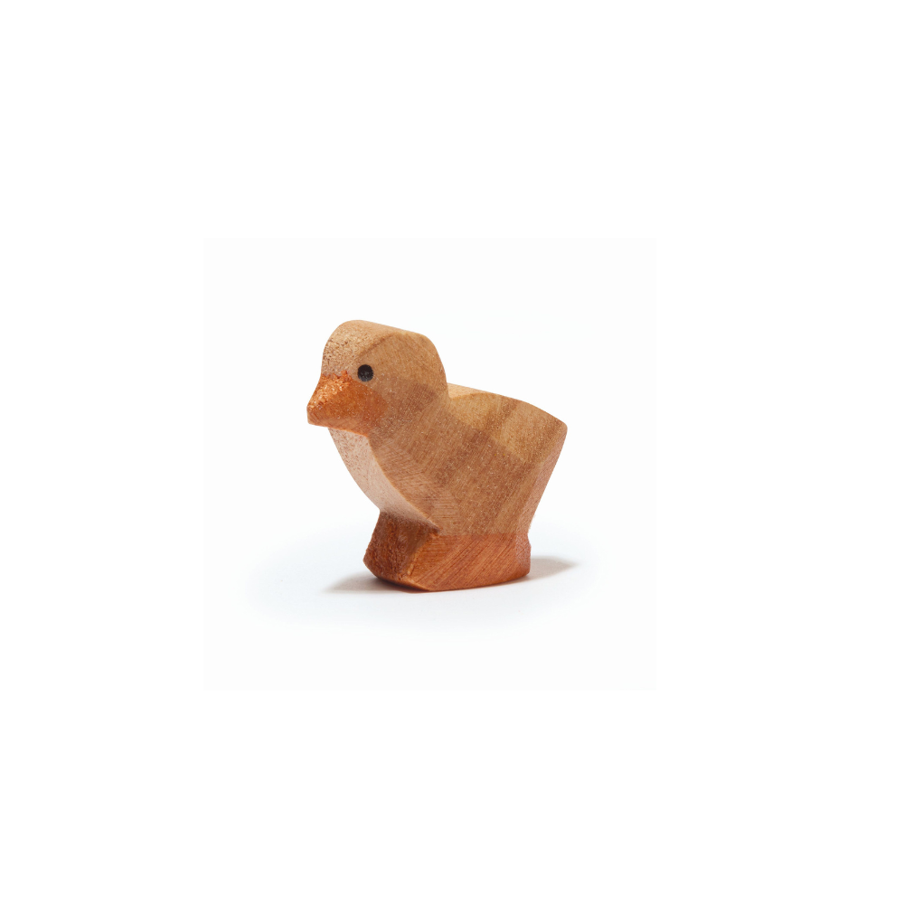 A small, handcrafted wooden chick figurine from the Ostheimer brand features a simple, smooth design and natural wood finish. The chick stands upright with a slight tilt to its body, showcasing a tiny carved beak and black dot eyes. Perfect for imaginative play, the background is plain and white.