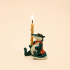The Later Gator Cake Topper—a charming ceramic alligator figurine dressed in a red vest and holding an upright lit beige candle—rests against a simple backdrop, making it an adorable handcrafted keepsake and the perfect collectible birthday decoration.