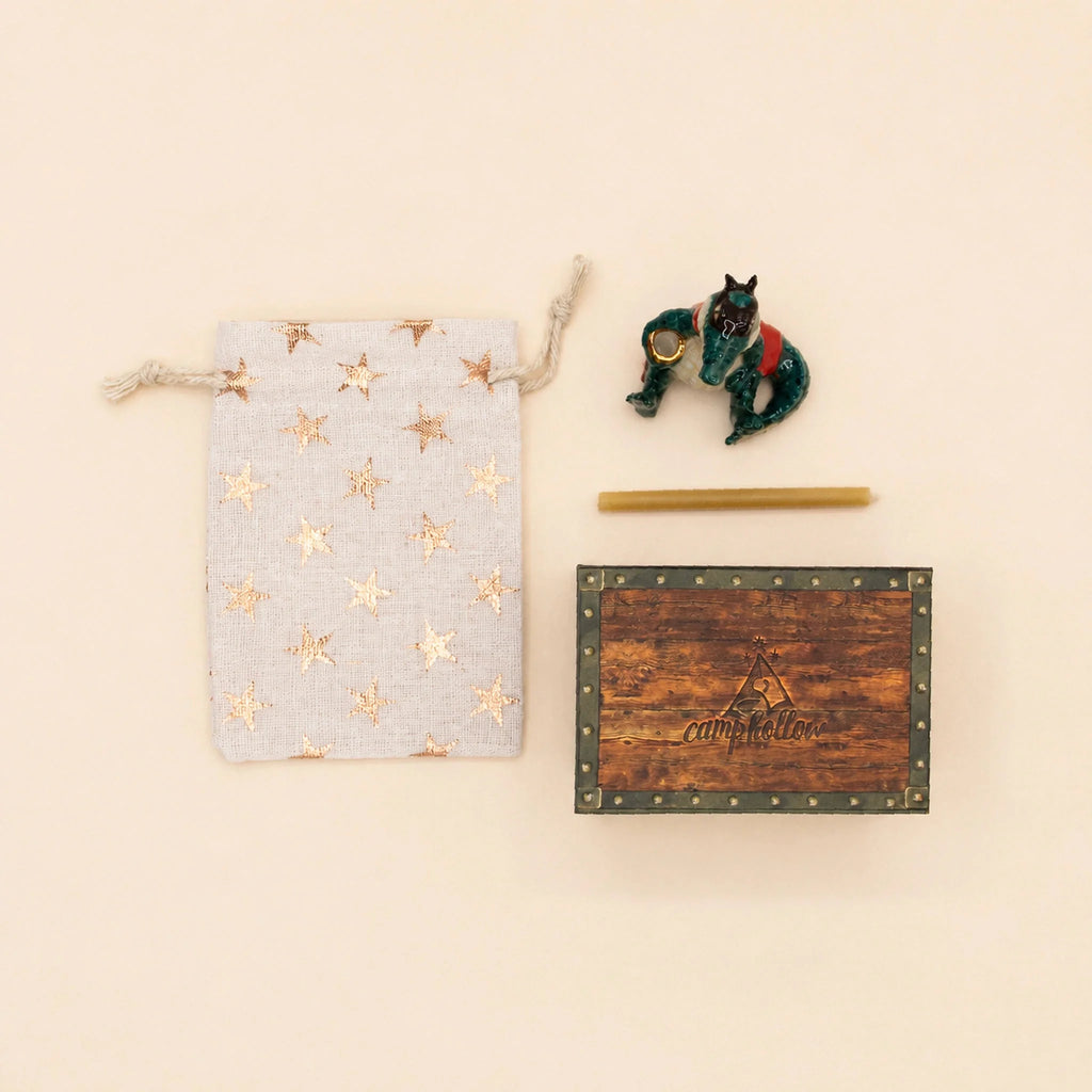 A flat lay featuring the Later Gator Cake Topper, a star-patterned drawstring pouch, a small dragon figurine, a yellow stick, and a wooden CampHallow box on a beige background—perfect as a collectible keepsake or hand-painted birthday decoration.