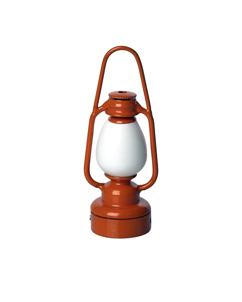 An orange and white traditional Maileg Lantern with a sturdy handle at the top. The lantern boasts a classic design with a glass enclosure protecting the flame. The base and framing are orange, while the glass and burner area are white, perfect for those who prefer non-rechargeable options.