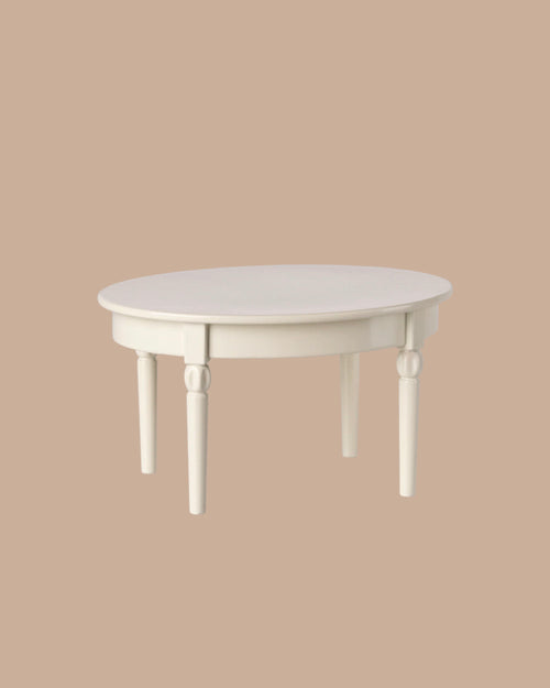 The PRE-ORDER: Vintage Dining Table, Mouse - Off White features a round white wooden design with detailed legs, showcased against a plain beige background. Estimated ship date is early October.