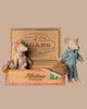 Two Maileg mice from the Maileg Family Room Set, one in a dress and one in pajamas, pose playfully on and beside a vintage-style "Havina Cigars" box, capturing the charming miniature world of Maileg.