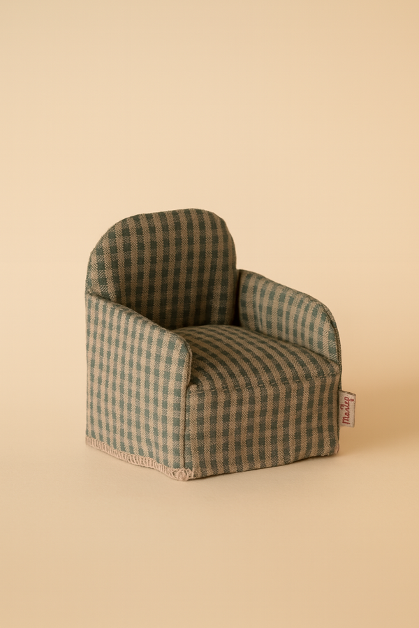 The Maileg Folding Chair, Mouse - Green Checker features a small green and beige checkered design, short arms, and a fabric tag. Ideal for dollhouse accessories or Gingerbread House furniture. Shown on a light beige background.