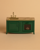The Maileg Kitchen - Dark Green is a miniature toy oven with a gold faucet, sink, and stovetop, plus an oven holding a small loaf of bread. Ideal for a mouse family's metal kitchen. Set against a solid beige background.
