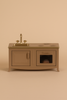 The Maileg Kitchen - Light Brown is a miniature toy kitchen set with a sink, faucet, stovetop, cabinet, and oven with a tiny loaf of bread—ideal for any mouse family—displayed against a beige background.