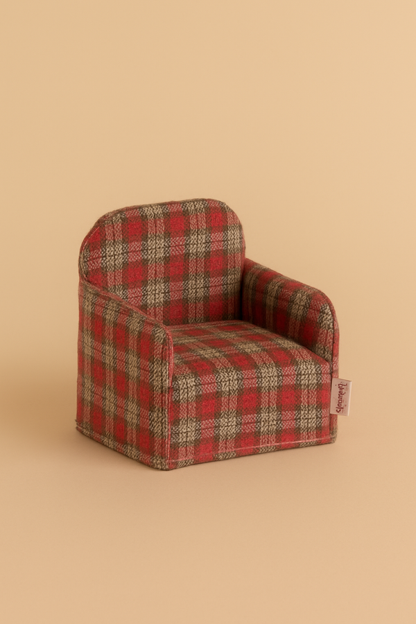 The Maileg Folding Chair, Mouse - Red Checker features a small red and brown plaid design. Photographed on a beige surface, it's ideal for dollhouse furniture or adding charm to your Maileg Gingerbread House display.