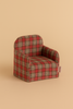 The Maileg Folding Chair, Mouse - Red Checker features a small red and brown plaid design. Photographed on a beige surface, it's ideal for dollhouse furniture or adding charm to your Maileg Gingerbread House display.