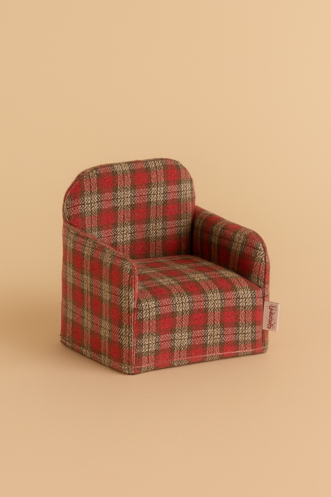 The Maileg Folding Chair, Mouse - Red Checker features a small red and brown plaid design. Photographed on a beige surface, it's ideal for dollhouse furniture or adding charm to your Maileg Gingerbread House display.