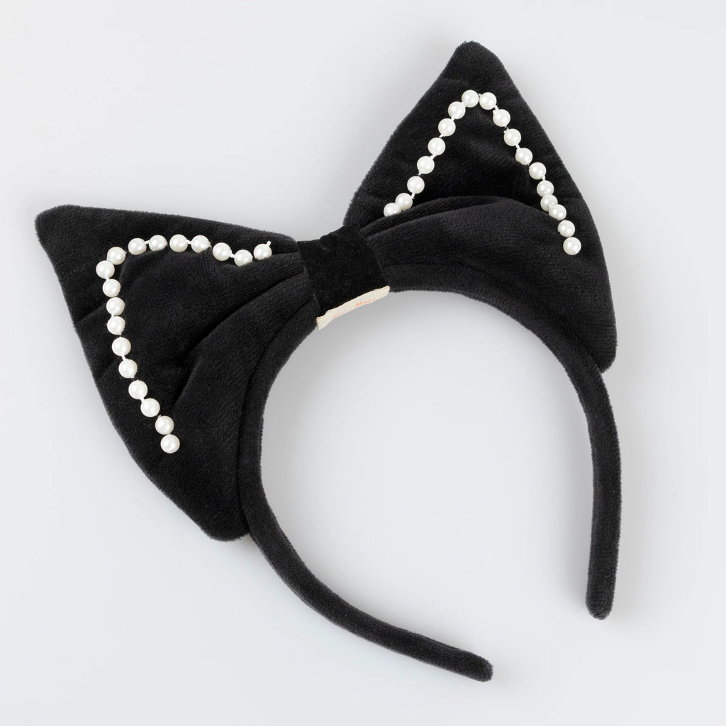 The Meri Meri Cat Costume headband features plush black cat ears outlined in faux pearls, ideal for Halloween costumes. Shown against a light gray background.