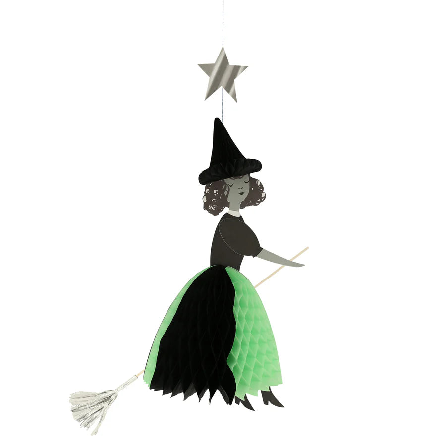 The Meri Meri Flying Honeycomb Witch Decoration is a whimsical, cartoon-like Halloween ornament that showcases a witch wearing a black hat and holding a broomstick. Her black and green dress, adorned with a honeycomb design, adds charm, while a shimmering silver star floats above her.