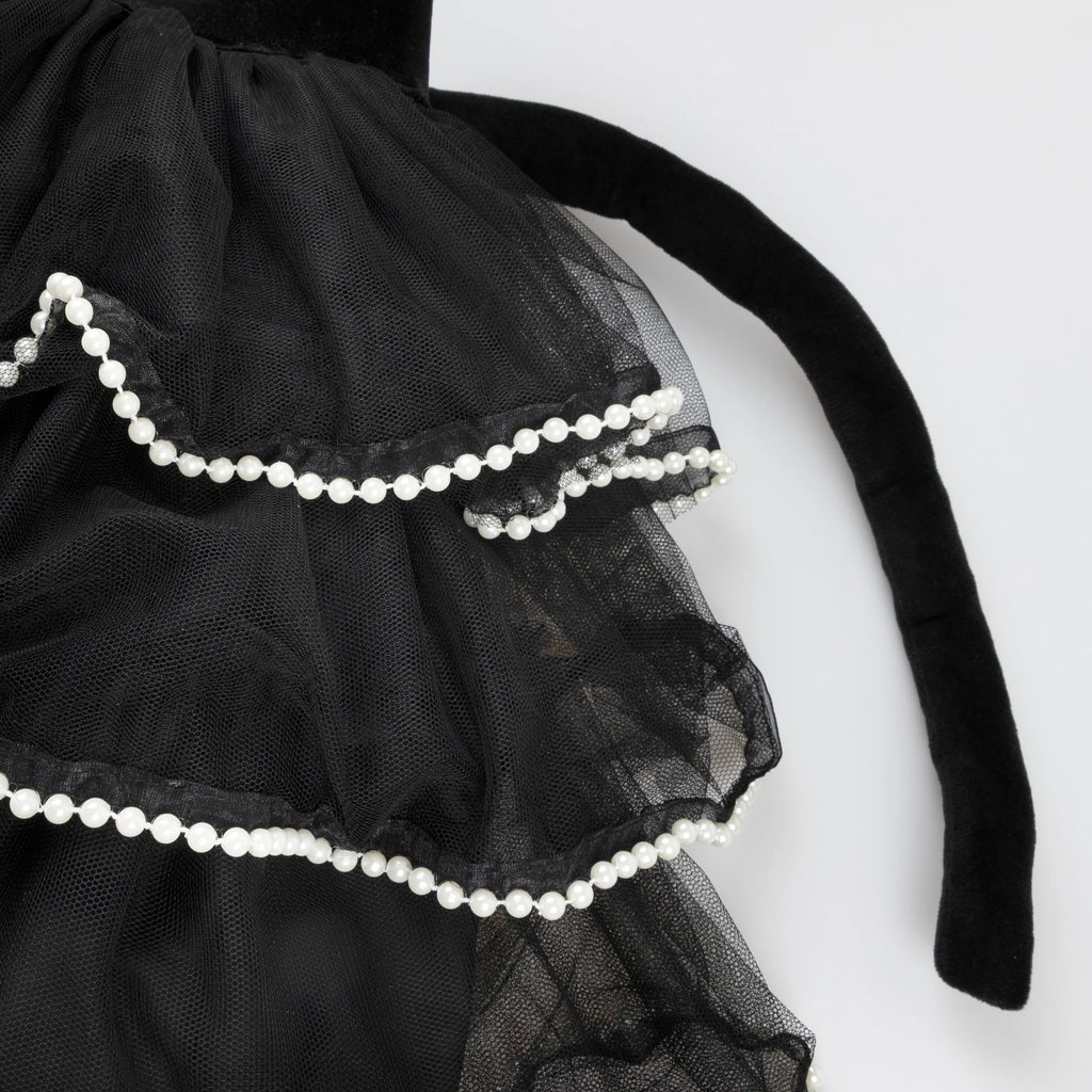 A close-up of layered black tulle fabric with ruffled edges, white pearl trim, and part of a black velvet bow from the Meri Meri Cat Costume—perfect for a whimsical Halloween look.