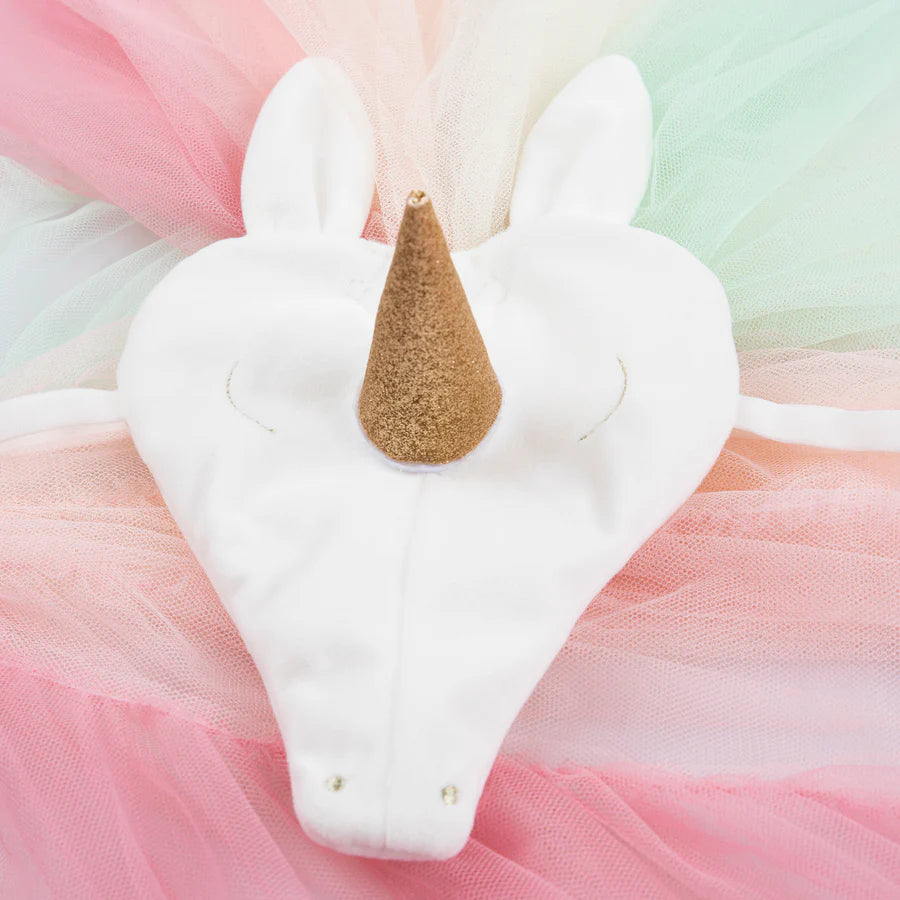 A detailed view of the Meri Meri Rainbow Unicorn Costume reveals a white unicorn-shaped mask adorned with a gold horn, all set against a vibrant, pastel tulle backdrop. This velvet headpiece showcases an exaggerated heart shape and two plush ears at the top.