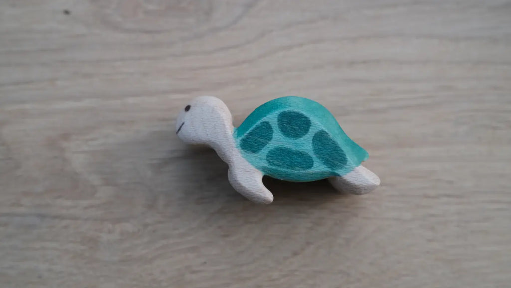 The Handmade Holzwald Sea Turtle, Small, features a green shell with light wood head and limbs. Ideal for open-ended play, this wooden toy rests on a light wooden surface.