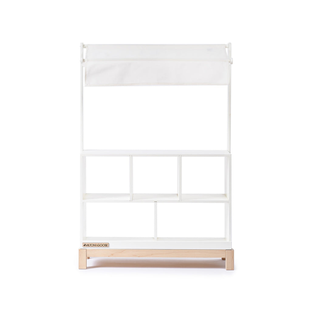 The Milton & Goose Market Stand, featuring three open shelves, a sturdy base, and a fabric canopy, is shown against a white background—ideal as a kids' play shop or stylish wooden market stand for any space.