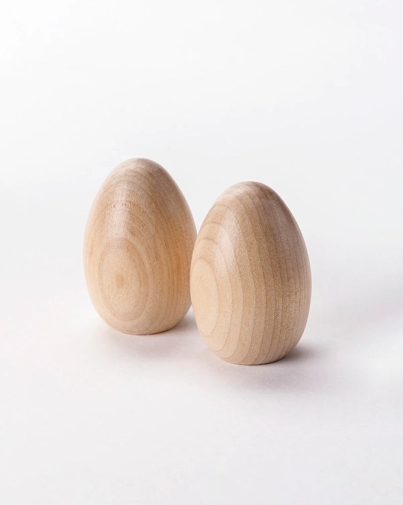 Two Milton & Goose wooden half dozen eggs with visible grain patterns, standing upright on a plain white background.