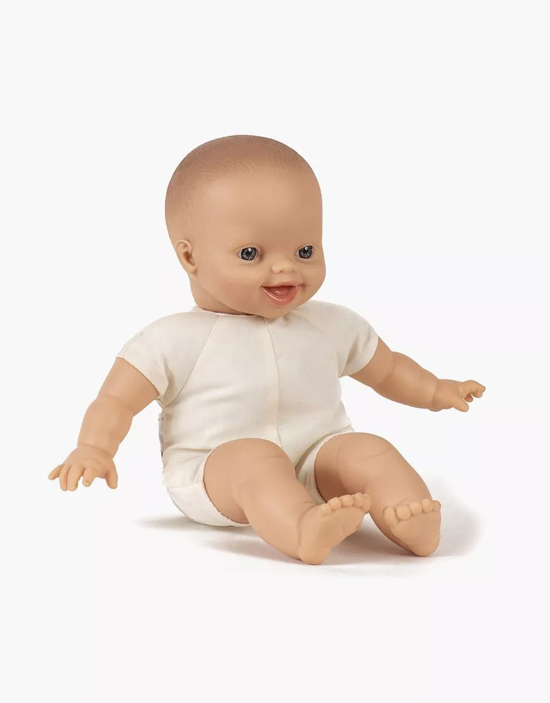 The Minikane Soft Body Doll (11") - Liv features a smiling expression, blue eyes, and light skin. Dressed in a simple white outfit, she sits with extended legs and open arms against a plain white background.