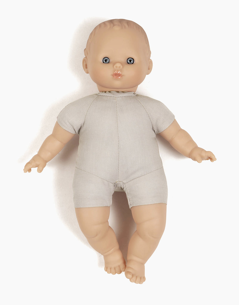 A Minikane Soft Body Doll (11") - Clarisse, perfect as a bedtime companion, features light-colored skin, blue eyes, and closed lips. Dressed in a plain, light gray one-piece outfit, this phthalate-free vinyl doll has short hair and is positioned facing forward with its arms slightly extended to the sides and its legs slightly apart.