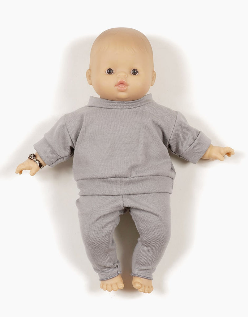 A Minikane Babies 11" doll with a bald head is dressed in a light grey outfit, resembling the Minikane Doll Clothing | Liam Set in Mouse Gray Jersey. The doll has a realistic appearance with detailed facial features and is posed lying on its back against a white background.