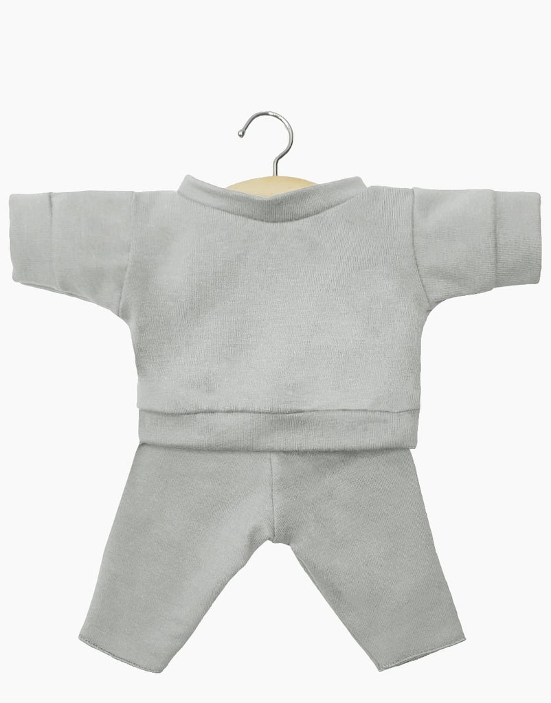 A small, light gray outfit for Minikane Babies or 11" dolls, consisting of a long-sleeved top and matching pants. The Minikane Doll Clothing | Liam Set in Mouse Gray Jersey is displayed on a wooden hanger with a metal hook, seen against a plain white background.